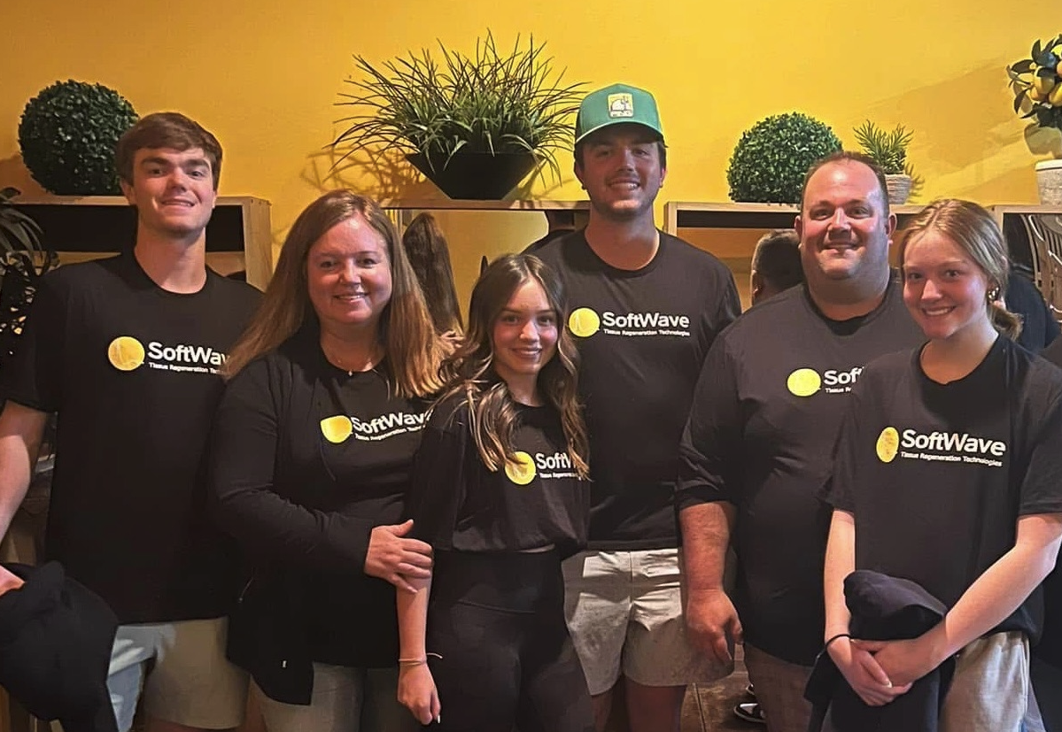 Dr. Kyle Bowers standing with the Bowers Chiropractic team in front of the office logo